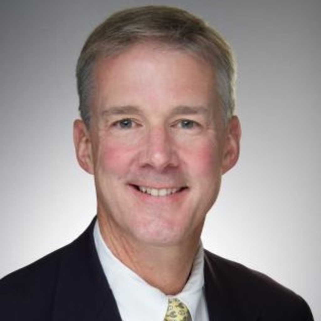 A photo of Dr. Matt Howard wearing a white coat, blue shirt, and tie in front of a gray background