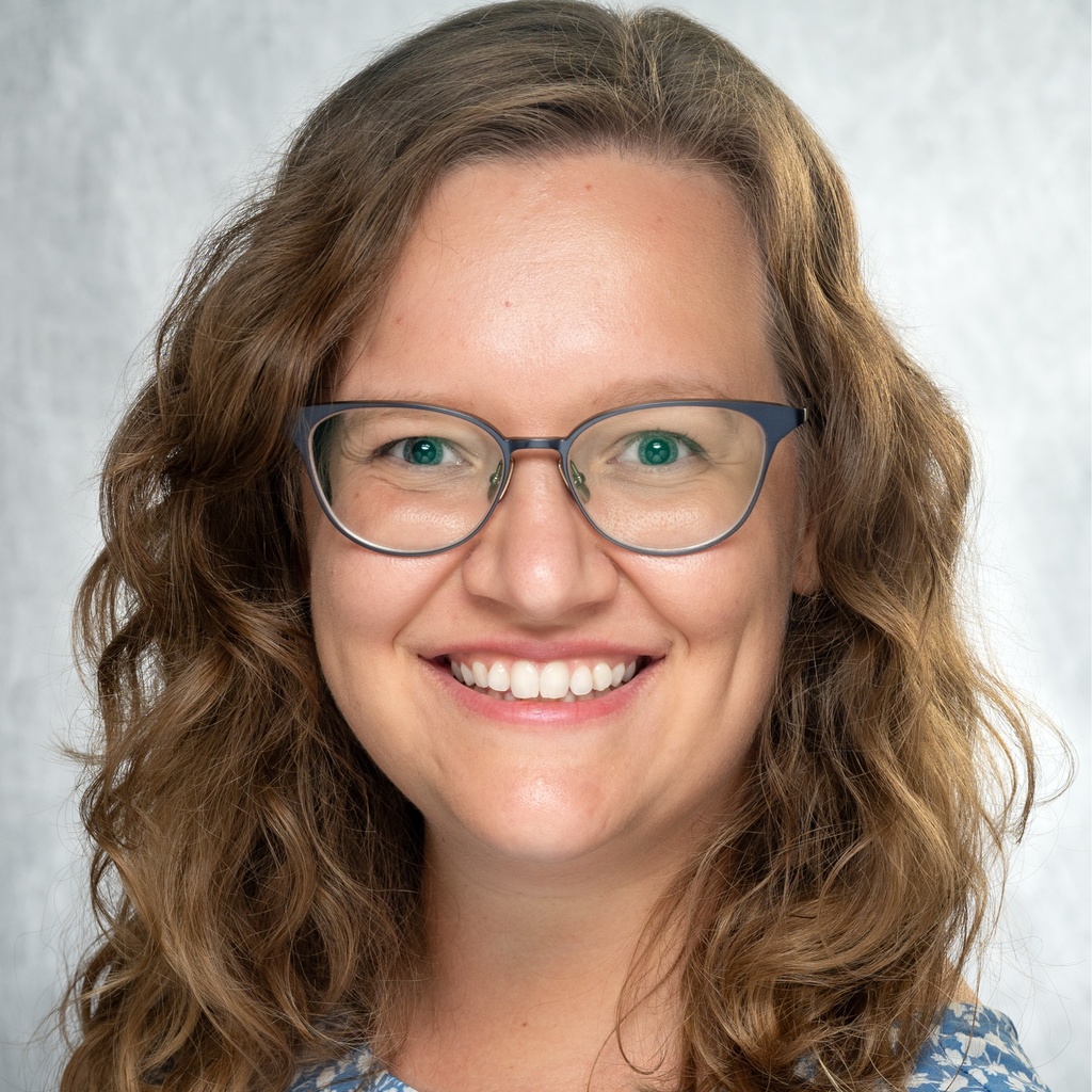 A photo of Dr. Deifelt Streese smiling, wearing a blue shirt in front of a gray background