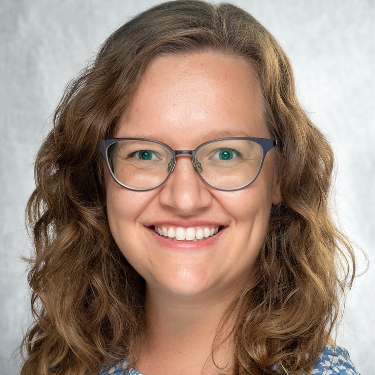 A photo of Dr. Deifelt Streese smiling, wearing a blue shirt in front of a gray background