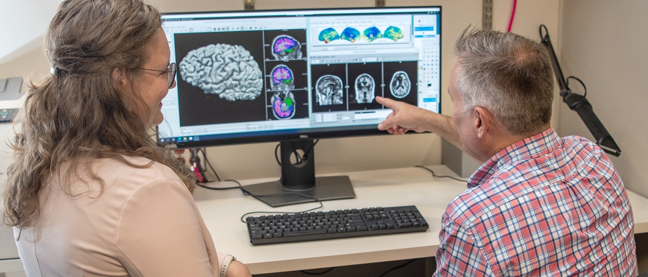 Dr. Deifelt Streese and Joel Bruss discussing brain images on a computer screen